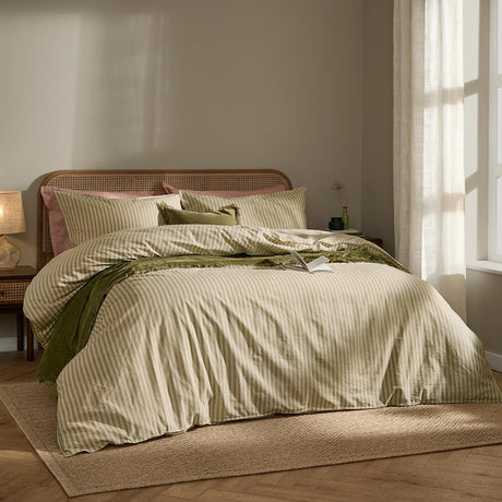 Marlow Stripe Cotton Printed Duvet Cover Set in Oregano/Shell features green-and-cream striped bedding, styled with a green velvet throw and pink and green cushions.