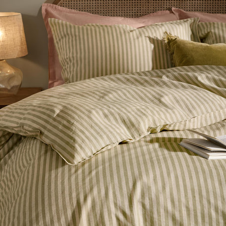 Marlow Stripe Cotton Duvet Cover Set in Oregano/Shell, styled on a bed with matching striped pillowcases, pink pillows, and a green velvet cushion in a bedroom setting.