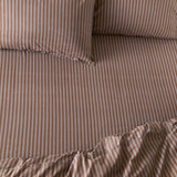 Marlow Stripe Printed Cotton Fitted Sheet in cocoa brown and vintage blue, showing a fine striped pattern on cotton fabric with matching pillowcases on a bed.