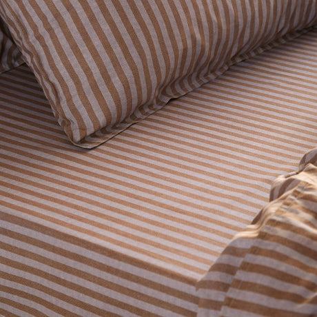 Marlow Stripe Printed Cotton Fitted Sheet in Cocoa, close-up of striped cotton fabric and pillowcase on a bed showing the fine brown and pale stripe pattern.
