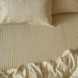 Marlow Stripe Printed Cotton Fitted Sheet in Oregano/Shell, shown on a made bed with matching striped pillowcases in soft green and cream tones.
