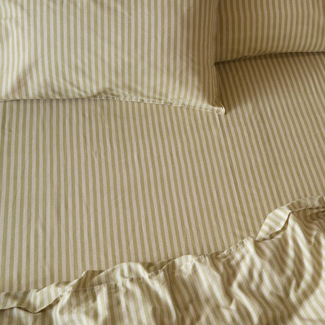Marlow Stripe Printed Cotton Fitted Sheet in Oregano/Shell, shown on a made bed with matching striped pillowcases in soft green and cream tones.