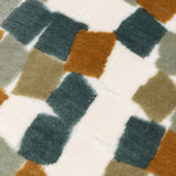 Close-up of the Metro Blocks Jacquard Velvet Cushion in green, showing raised velvet blocks in teal, rust and sage over a cream woven ground.
