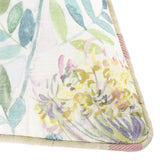 Close-up corner of the Morning Chorus Linen Cotton Cushion in Elderberry, showing a hand-painted watercolour floral and foliage design in green, pink and yellow with woven piped edging.