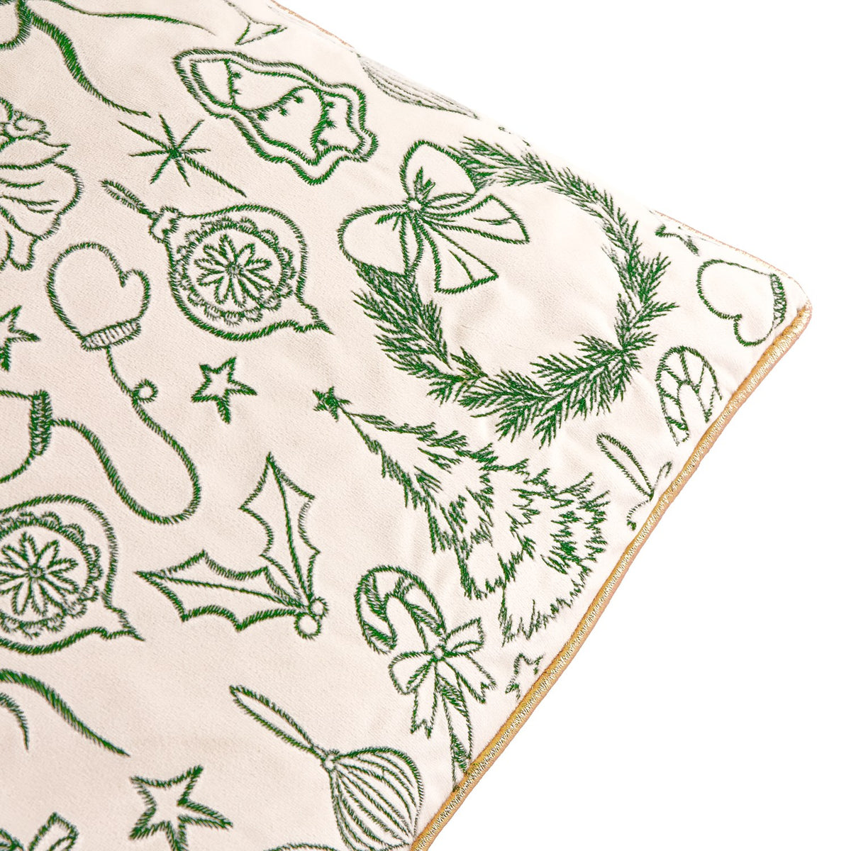 Close-up of the Merry Christmas Embroidered Velvet Cushion in ecru, showing dark green embroidered wreaths, trees, bells and holly with a gold piped edge trim.