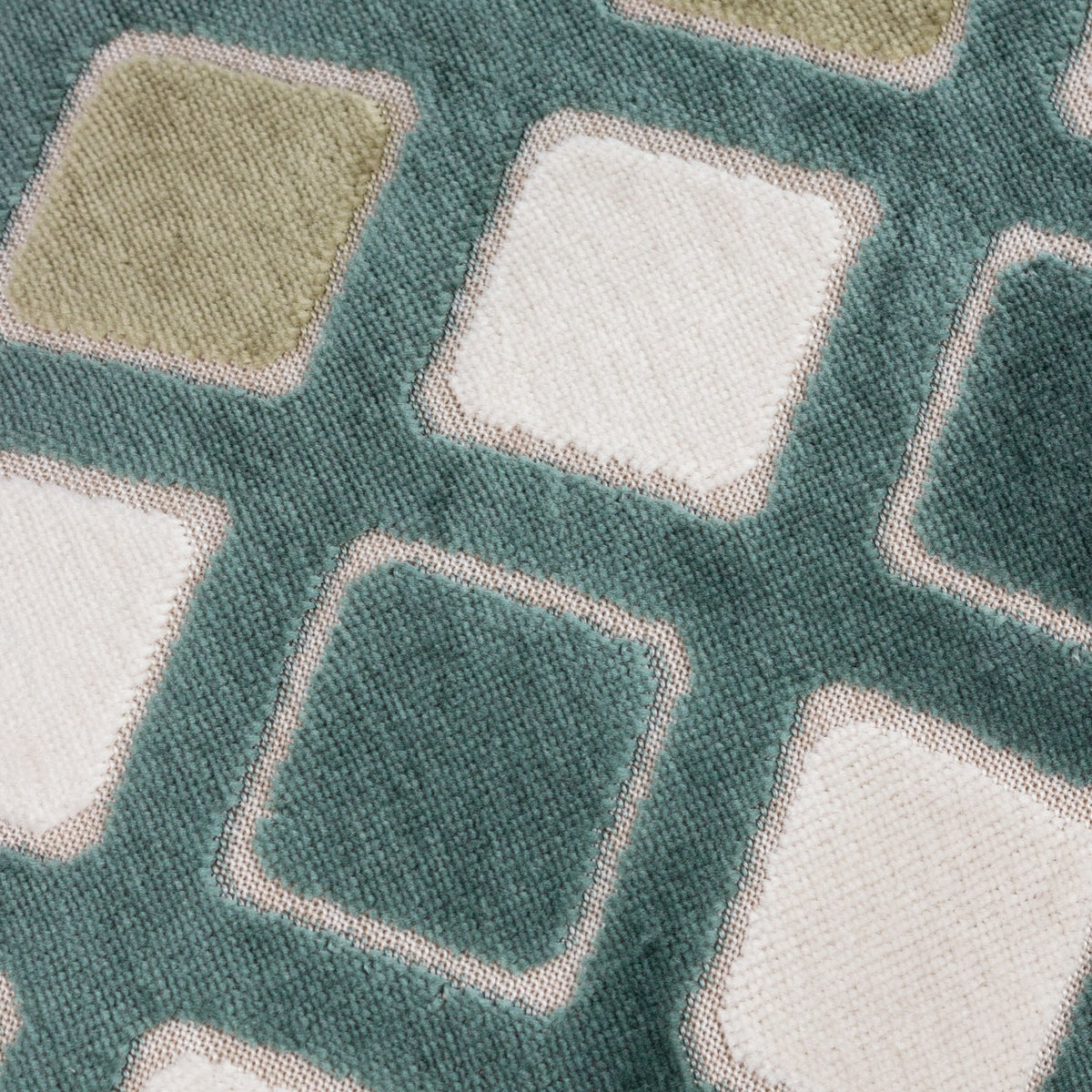 Metro Diamond Jacquard Velvet Cushion in green, close-up showing woven diamond pattern with sage, cream and white squares on a teal-green velvet ground.