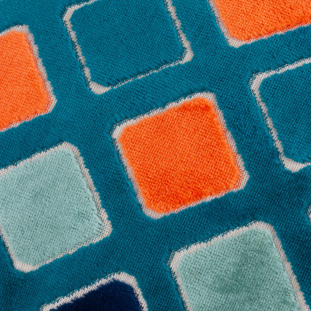 Close-up of the Metro Diamond Jacquard Velvet Cushion, showing a teal ground with a diamond grid pattern in orange, sage, and navy velvet squares outlined in cream stitching.
