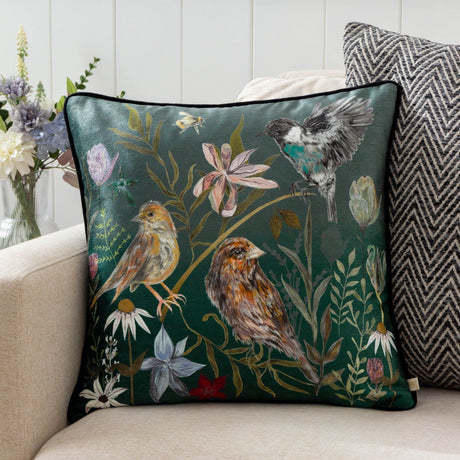 Meadow Bloom Animal Chenille Cushion in teal, showing hand-painted birds and wildflowers on a deep green square cushion, styled on a living room sofa.