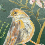 Meadow Bloom Animal Chenille Cushion in teal, close-up of a hand-painted bird among trailing foliage and leaves on a deep green chenille fabric ground.