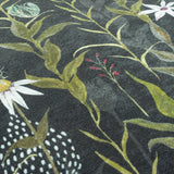 Meadow Bloom Floral Chenille Cushion in Multicolour, close-up of dark chenille fabric with green leafy stems, white daisies and red berry sprigs against a near-black ground.
