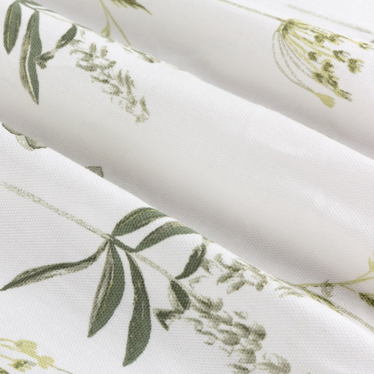 Close-up of Meadow Floral Cotton Pencil Pleat Curtains in white cotton Panama, folded to show a wildflower print with green leaves and sprigs.