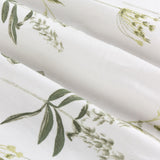 Close-up of Meadow Floral Cotton Pencil Pleat Curtains in white cotton Panama, folded to show a wildflower print with green leaves and sprigs.
