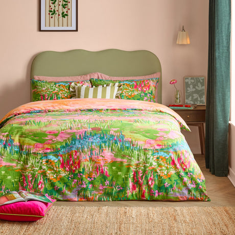 Meadow Escape reversible duvet cover set on a bed with green upholstered headboard, showing a painterly wildflower meadow print in green, pink, orange and blue.