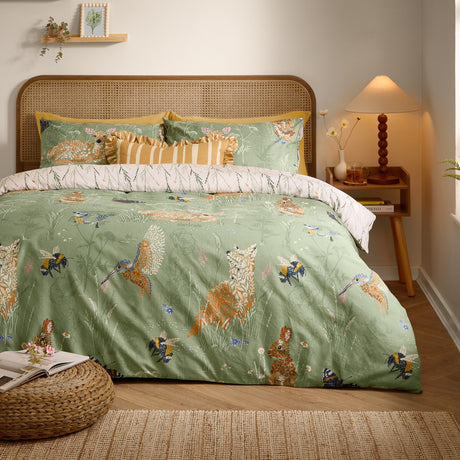 Meadow Flora Reversible Animal Duvet Cover Set in green, shown on a bed with woodland creatures like foxes, hares and hummingbirds in a rattan-headboard bedroom.