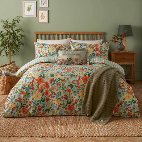 Meadow Haze Reversible Gingham Duvet Cover Set in green shown on a bed with wildflower-print bedding, gingham trim, and a green waffle throw in a sage-walled bedroom.