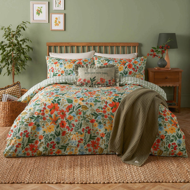 Meadow Haze Reversible Gingham Duvet Cover Set in green shown on a bed with wildflower-print bedding, gingham trim, and a green waffle throw in a sage-walled bedroom.