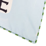 Close-up of the Mediterranean Olive reversible polyester cushion corner, showing pale sky-blue fabric with black lettering and green striped piped trim edging.