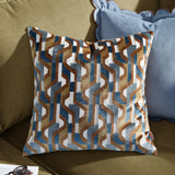 Metro Prism Jacquard Velvet Cushion in Ginger, square with a geometric jacquard pattern in ginger, teal blue, slate grey and cream, shown on an olive sofa beside a blue scalloped cushion.