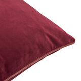 Close-up of the Meridian square velvet cushion in burgundy with contrasting slipper pink piped trim along the edge, shown on a plain white background.