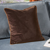 Meridian Plain Velvet Cushion in chocolate brown with contrasting caramel piped trim, shown on a light blue sofa.