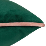 Close-up of the Meridian velvet cushion in emerald green with a contrasting blush pink piped edge, shown on a plain white background.