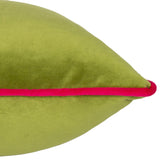 Close-up of the Meridian Plain Velvet Cushion in lime green, showing the pointed corner edge with a contrasting hot pink piped border, against a plain white background.