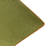 Close-up of the Meridian Plain Velvet Cushion corner in olive green velvet with contrasting ginger piped trim along the edge, shown on a plain white background.