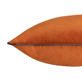 Close-up of the Meridian Plain Velvet Cushion in burnt pumpkin orange, showing the corner point and mocha brown piped edge detail on a white background.