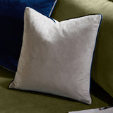 Meridian Plain Velvet Cushion in silver grey with navy piped edging, shown on an olive green sofa beside a navy blue cushion.