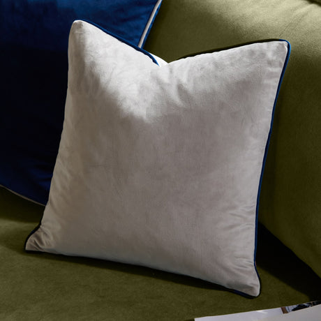 Meridian Plain Velvet Cushion in silver grey with navy piped edging, shown on an olive green sofa beside a navy blue cushion.