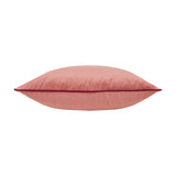 Meridian plain velvet cushion in coral pink, shown side-on with a contrasting burgundy piped edge trim, on a plain white background.