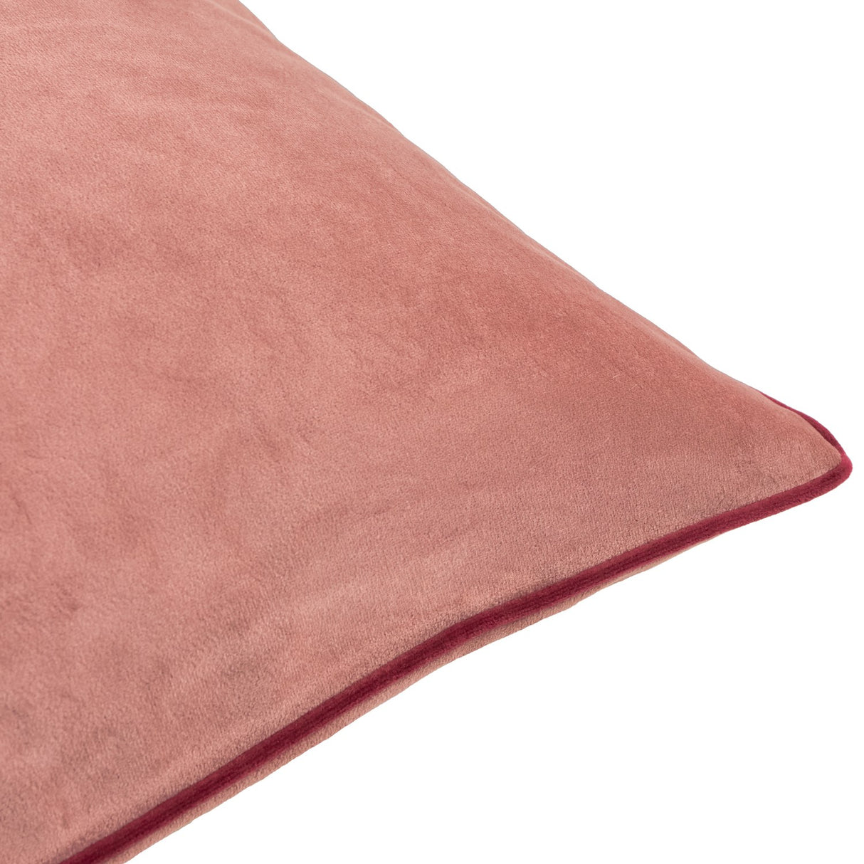 Close-up of the Meridian plain velvet cushion in soft coral pink with a contrasting burgundy piped trim along the edge, shown on a plain white background.