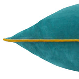 Close-up of the Meridian square cushion's pointed corner in deep teal velvet, edged with a contrasting ochre-gold piped trim, on a plain white background.