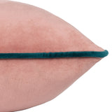 Close-up of the Meridian velvet cushion's pointed corner, showing blush pink fabric with a contrasting deep teal piped edge, on a plain white background.