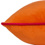 Close-up of the Meridian Plain Velvet Cushion in clementine orange with a contrasting hot pink piped edge, shown on a plain white background.