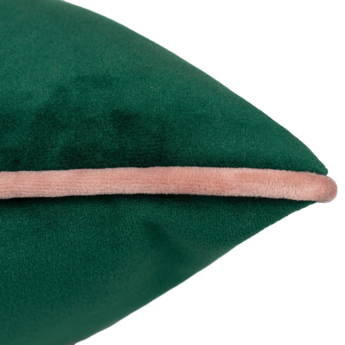 Close-up of the Meridian velvet cushion in emerald green with a blush pink piped edge, showing the fabric texture on a plain white background.