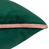 Close-up of the Meridian velvet cushion in emerald green with a blush pink piped edge, showing the fabric texture on a plain white background.