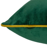 Close-up of the Meridian velvet cushion in emerald green, showing the soft velvet pile and contrasting gold-toned piped edge along the seam, on a plain white background.