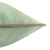 Close-up of the Meridian sage green velvet cushion corner, showing smooth polyester velvet pile with a contrasting taupe piped trim, on a plain white background.