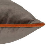 Close-up of the Meridian velvet cushion's corner, showing mocha brown fabric with a pumpkin orange piped edge, on a plain white background.