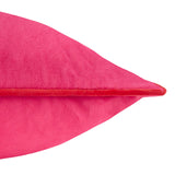 Close-up of the Meridian plain velvet cushion in hot pink, showing the smooth fabric texture and contrasting red piped edge trim on a white background.