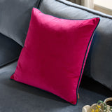 Meridian Plain Velvet Cushion in raspberry pink with contrasting teal piped edge, square velvet fabric design, shown propped on a grey sofa.