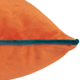 Close-up of the Meridian Plain Velvet Cushion in tiger orange, showing the soft velvet pile and contrasting teal piped edge on a plain white background.