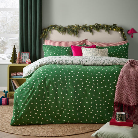 Merry Christmas cotton duvet cover set on a bed, green polka dot side shown with reversible festive sketch print pillowcases, in a bedroom with holiday decor.