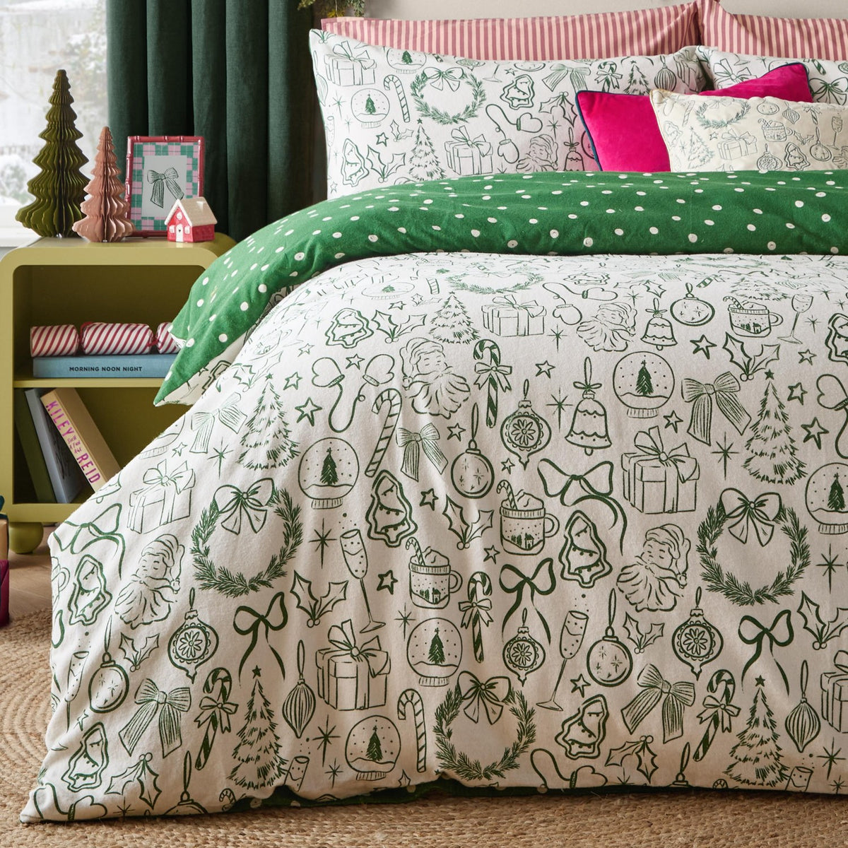 Merry Christmas Cotton Spotted Duvet Cover Set in oat and green, styled on a bed with festive sketch print of trees, gifts and baubles, paired with a green polka dot reverse and pink cushions.