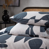 Cotton Abstract Duvet Cover Set in Dusk featuring off-white bedding with a slate blue abstract print on the duvet cover and matching pillowcases, styled on a bed with a rattan headboard.