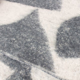 Close-up of the Meta Jacquard Polyester Throw in Dusk, showing soft blue-grey abstract shapes on a cream faux mohair fabric with a visible stitched edge.