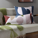 Meta Jacquard Polyester Throw in olive and cream draped over a boucle sofa, with matching rectangular cushions in navy, blush, and rust tones nearby.