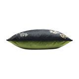 Midnight Garden velvet cushion shown side-on, with black floral-printed front and plain green velvet back, edged in black piping, on a white background.