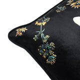 Close-up corner view of the Midnight Garden Animal Velvet Cushion in black, showing velvet fabric with printed botanical stems and cream-amber star-shaped blooms, edged with a piped seam.